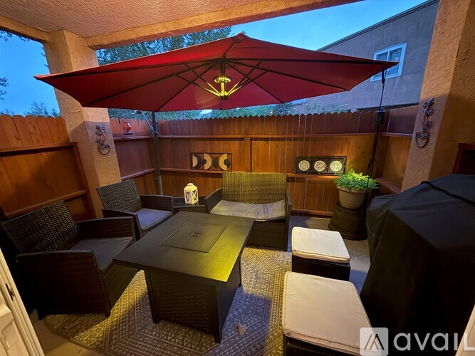 A patio with a table and chairs under a red umbrella.
