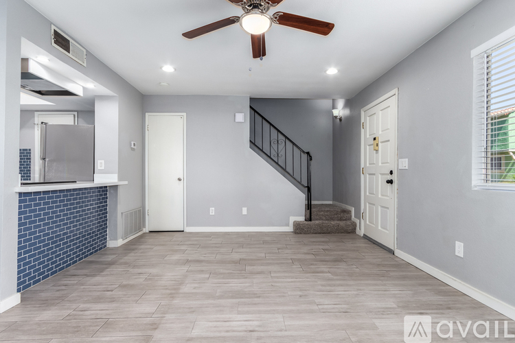A spacious room with a staircase and a ceiling fan.