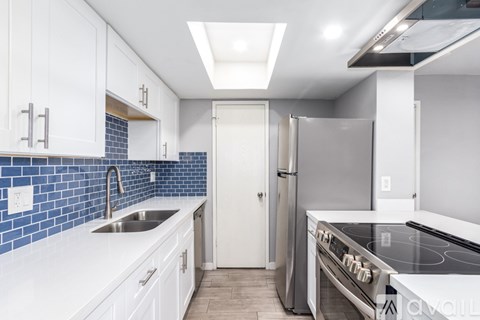 A kitchen with white cabinets and a blue tile backsplash.