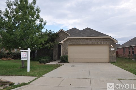 A house with a garage and a sign in front of it.