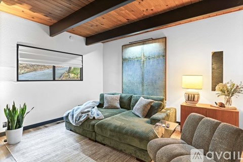 A living room with a green couch and a grey armchair.