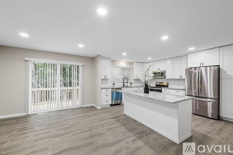 A modern kitchen with a stainless steel refrigerator and wooden flooring.
