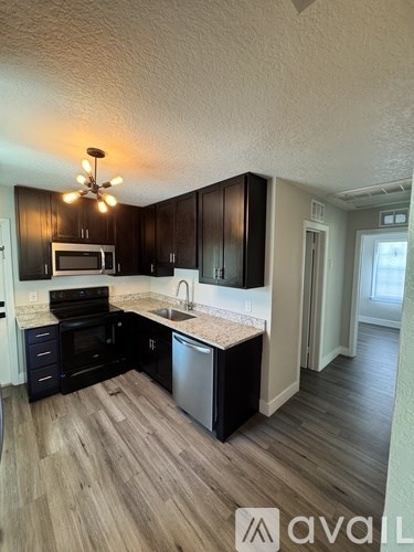 A kitchen with black cabinets and a stainless steel dishwasher.