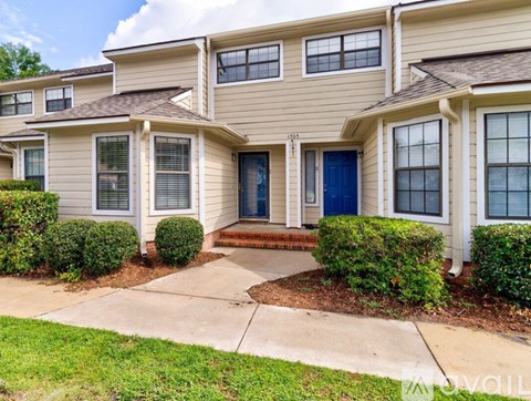 A beige house with a blue door and windows.