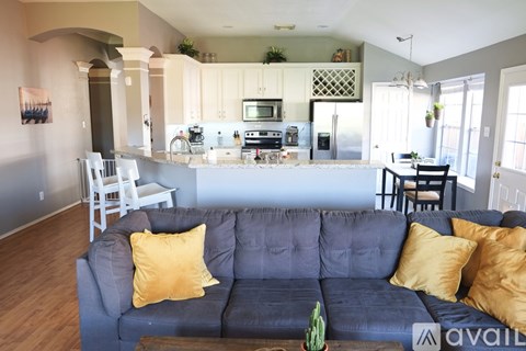 A living room with a grey couch and yellow pillows.