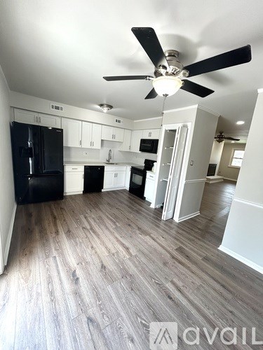 A kitchen with a black fridge and white cabinets.