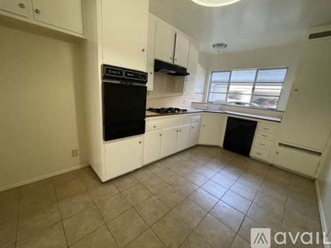 A kitchen with white cabinets and black appliances.