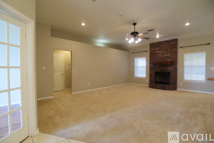 A spacious living room with a fireplace and a ceiling fan.