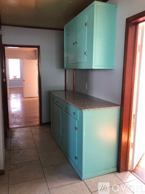 A kitchen with teal cabinets and a counter top.