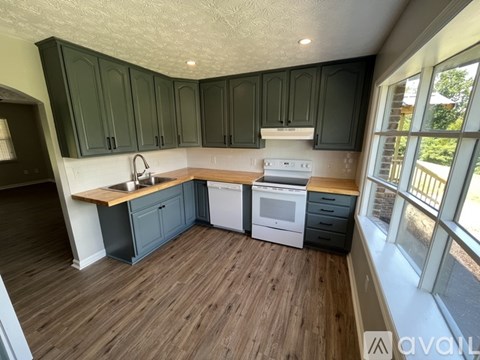 A kitchen with dark green cabinets and a white stove top oven.