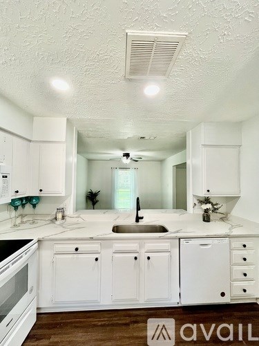 A kitchen with white cabinets and a wooden floor.