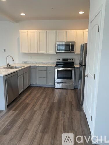 A kitchen with white cabinets and a wooden floor.