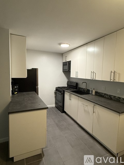 A kitchen with white cabinets and a black countertop.