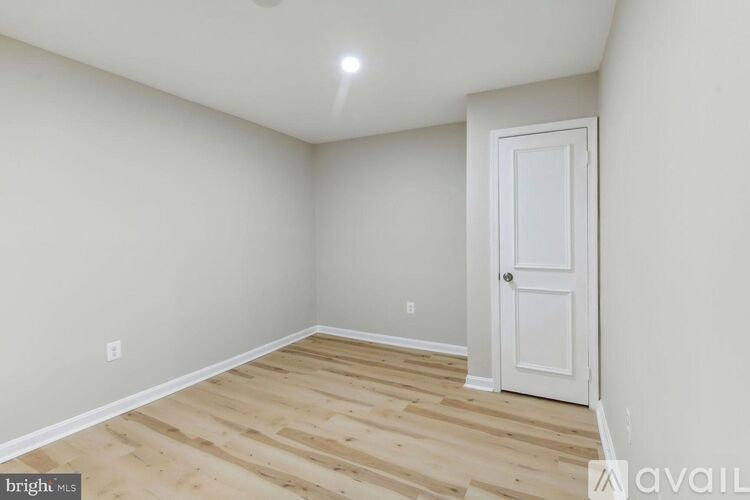 A room with a white door and wooden flooring.