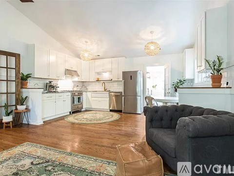A living room with a grey couch and a kitchen area in the background.