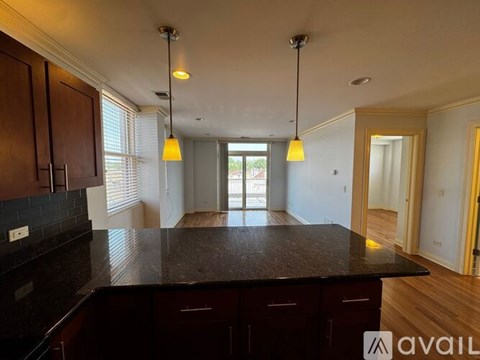 A spacious room with wooden flooring and a bar area in the corner.
