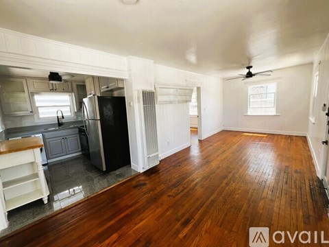 A kitchen with a refrigerator, sink, and wooden floors.