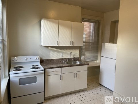 A kitchen with a stove, sink, and cabinets.