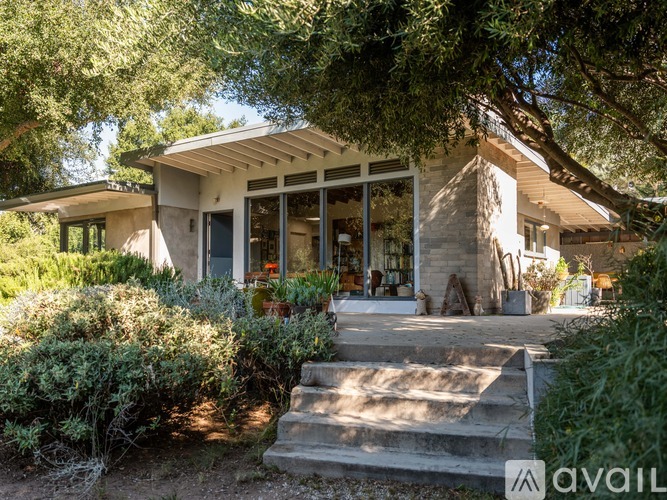A house with a front yard and a tree in front of it.
