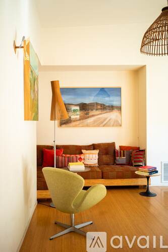 A living room with a yellow chair and a painting on the wall.