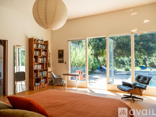 A bedroom with a large bed and a view of the backyard through the sliding glass doors.