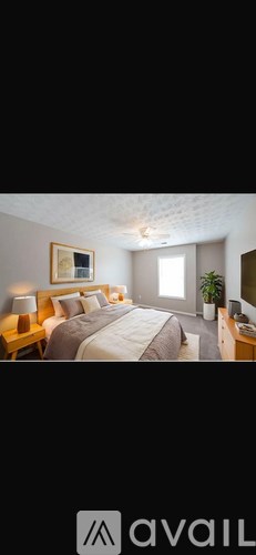 A bedroom with a large bed and a plant on the nightstand.