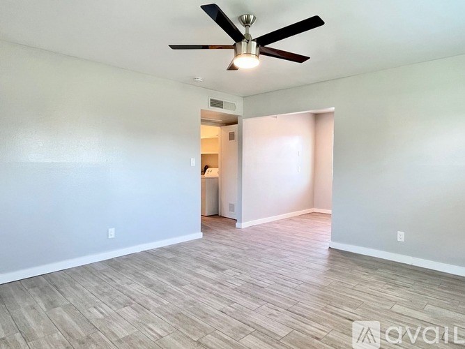 A room with a ceiling fan and light fixture, and a doorway leading to another room.