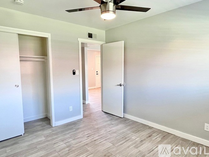 A room with a ceiling fan and a door leading to another room.