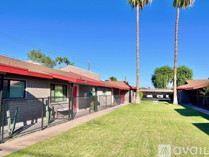 A sunny day at a park with palm trees and a building with a red roof.