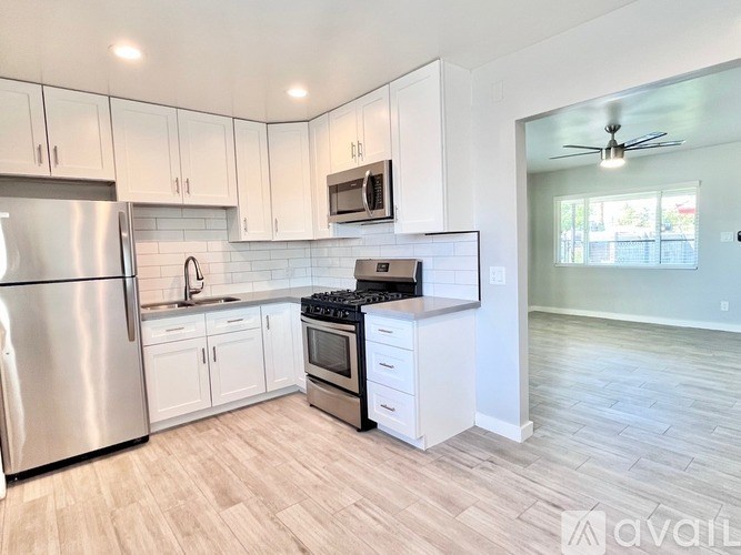 A kitchen with white cabinets and a stainless steel refrigerator.