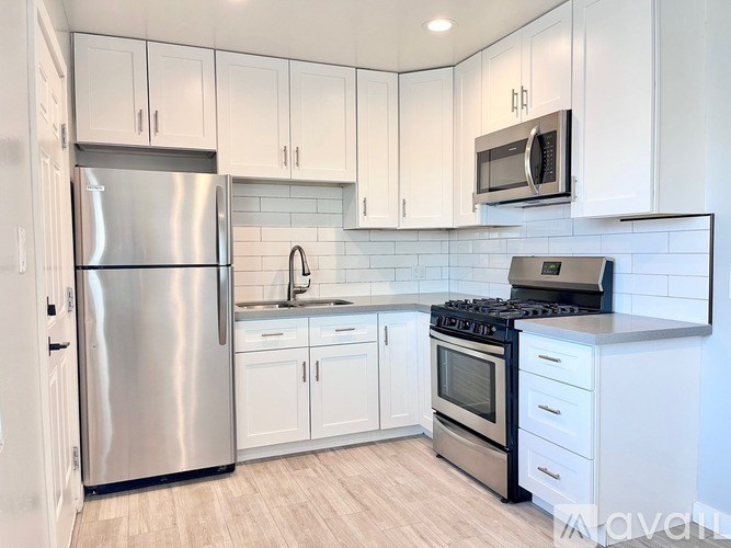 A kitchen with white cabinets and a stainless steel refrigerator.