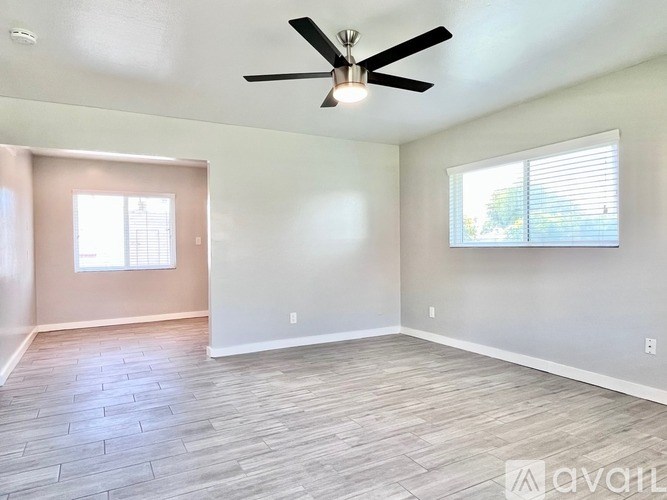 A room with a ceiling fan and a window with blinds.