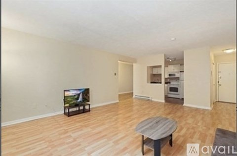 A living room with a wooden floor and a television on a stand.