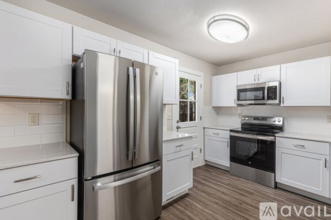 A kitchen with white cabinets and a stainless steel refrigerator.