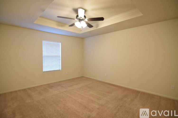 A spacious room with wooden floors and a ceiling fan.