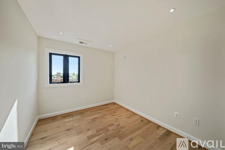 A room with wooden flooring and a window overlooking a cityscape.