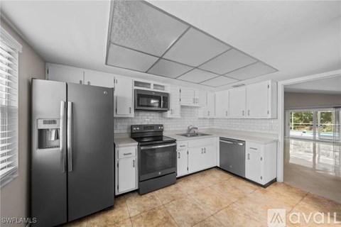 A kitchen with white cabinets and a black refrigerator.