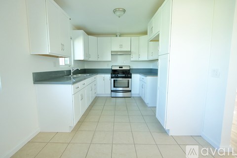 A kitchen with white cabinets and a tiled floor.