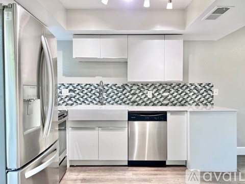 A modern kitchen with white cabinets and a checkered backsplash.