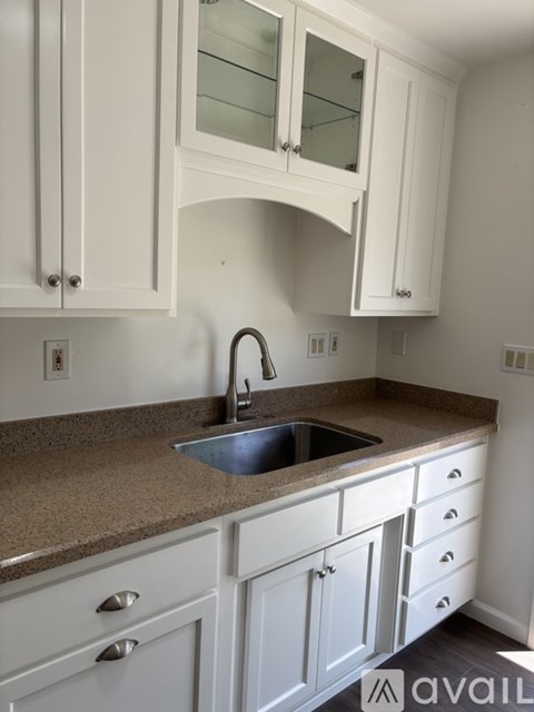 A kitchen with white cabinets and a granite countertop.