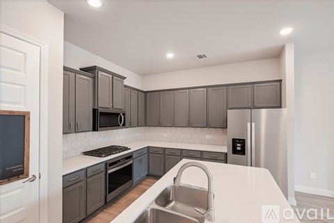 A kitchen with a white counter top and a stainless steel refrigerator.
