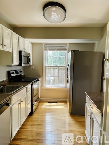A kitchen with wooden floors and white cabinets.