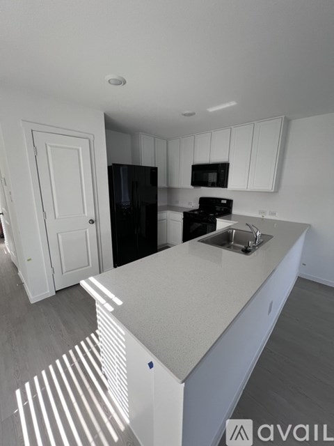 A kitchen with white cabinets and a black fridge.