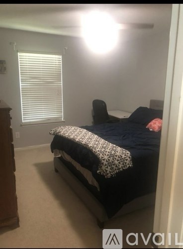 A bedroom with a bed, chair, and a window with blinds.