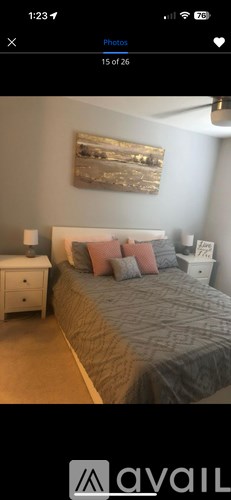 A bedroom with a bed, nightstand, and a painting on the wall.