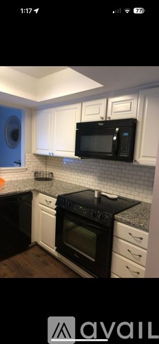 A kitchen with black appliances and white cabinets.