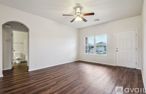 A room with a ceiling fan and wooden flooring.