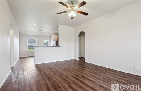 A spacious room with a ceiling fan and wooden flooring.