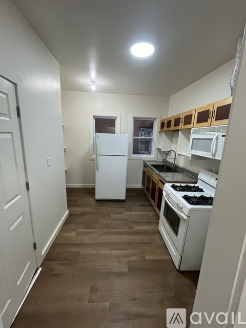 A kitchen with white appliances and wooden floors.