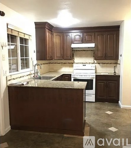 A kitchen with brown cabinets and a white stove top oven.